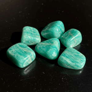 Polished tumbled Amazonite feldspar silicate triclinic on black matte background, elegant crystal stones.
