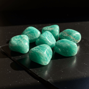 Polished tumbled Amazonite feldspar silicate triclinic on black matte background, elegant crystal stones.