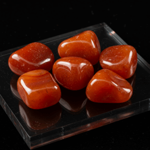 Polished tumbled Carnelian quartz silicate hexagonal on black matte background, elegant crystal stones.
