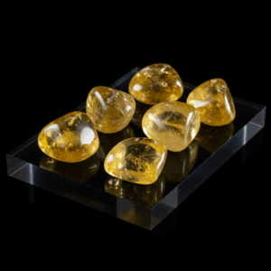Polished tumbled Citrine quartz silicate trigonal on black matte background, elegant crystal stones.