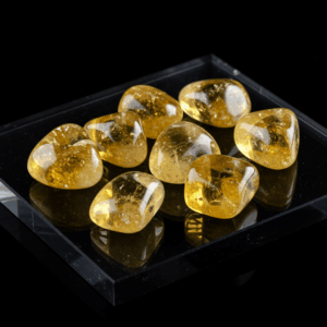 Polished tumbled Citrine quartz silicate trigonal on black matte background, elegant crystal stones.