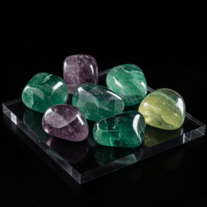 Polished tumbled Fluorite halide isometric cubic on black matte background, elegant crystal stones.