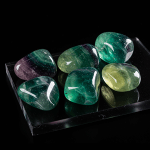Polished tumbled Fluorite halide isometric cubic on black matte background, elegant crystal stones.