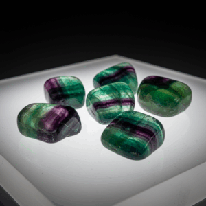 Polished tumbled Fluorite halide isometric cubic on white matte background, healing crystal stones.