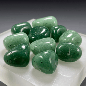 Polished tumbled Green Aventurine quartz silicate trigonal on white matte background, healing crystal stones.
