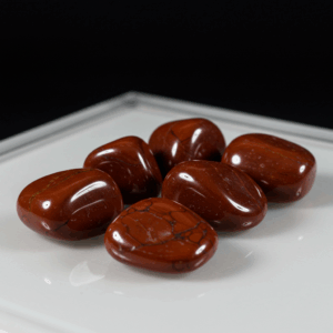 Polished tumbled Red Jasper quartz silicate hexagonal on white matte background, healing crystal stones.